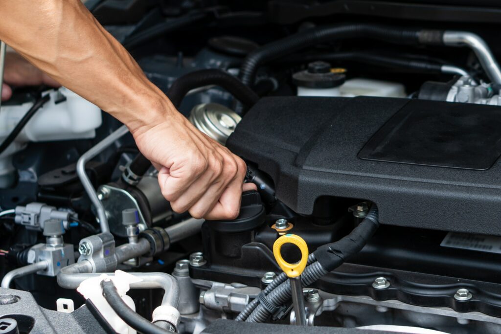 Hand of car machanic checking oil and oil change in car engine and car maintenance in garage.